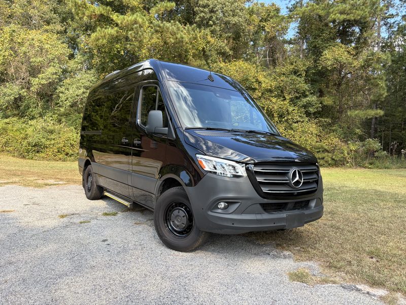 Front three quarter view of CE1, a black Mercedes-Benz Sprinter, parked outdoors